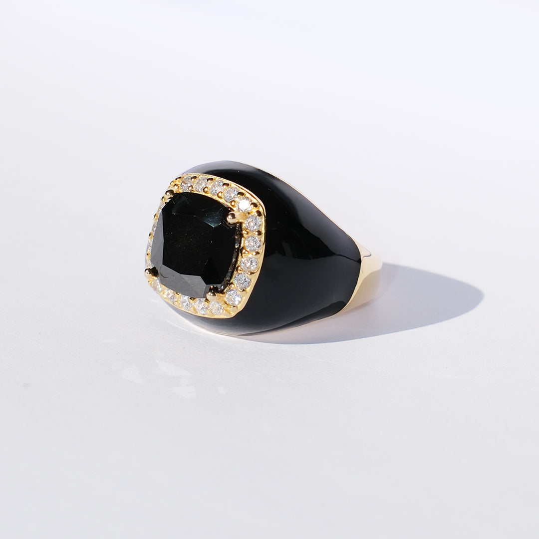 Black ring with a large gemstone and diamond-studded band on a white background