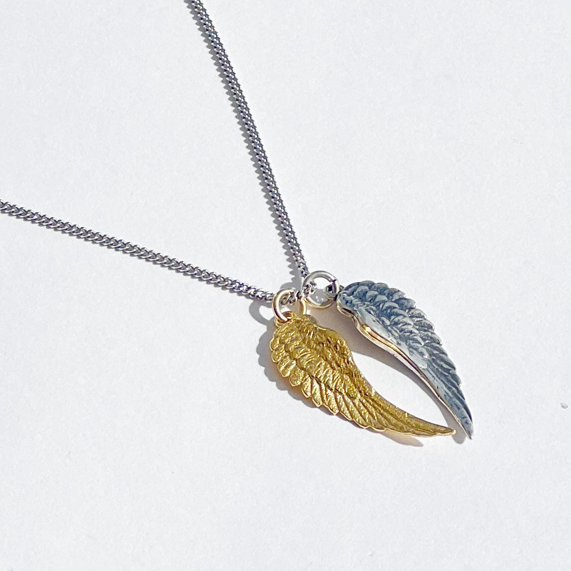 Pair of sterling silver and 18kt gold angel wing necklace with two separate wing charms on adjustable curb chain by Angel Rocks