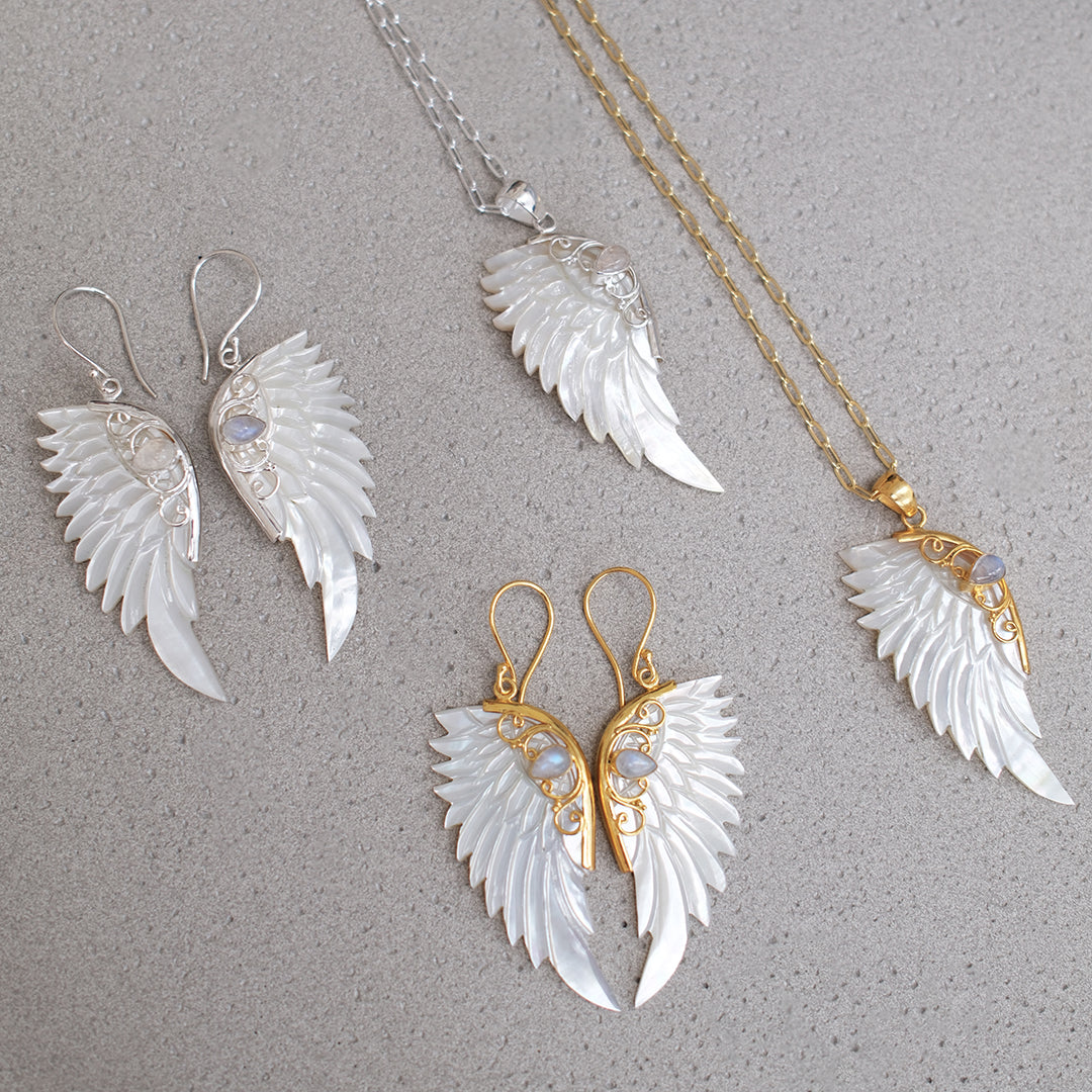 Sterling silver hand carved wing necklace with mother of pearl pendant and moonstone detail sterling silver chain, shown with earrings and gold hand carved wing necklace, statement jewellery by Angel Rocks