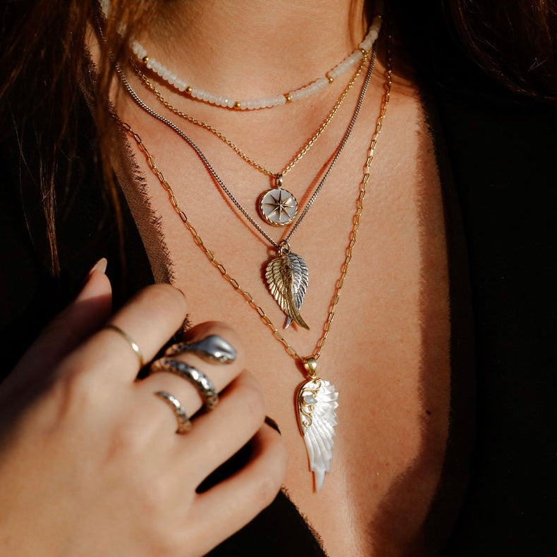 Gold hand carved wing necklace with mother of pearl pendant and moonstone detail on 18kt gold plated sterling silver chain, styled with various angel rocks rock n roll inspired necklaces, statement jewellery by Angel Rocks